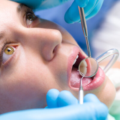 Dentist surgery closeup of woman's open mouth with dental tools